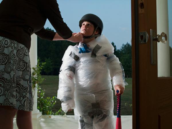 a boy wrapped in bubble wrap and wearing a bicycle helmet
