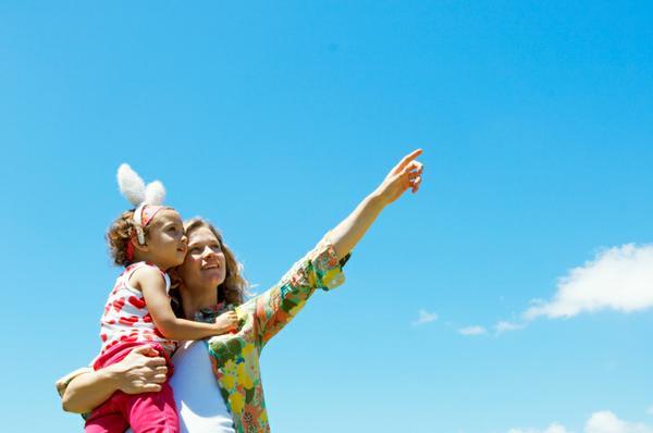 image of mother holding her daughter, who is wearing bunny ears, pointing toward the sky