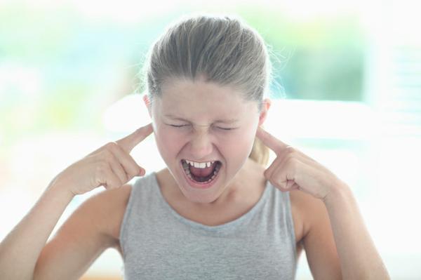  a young girl screaming, with her fingers stuck in her ear