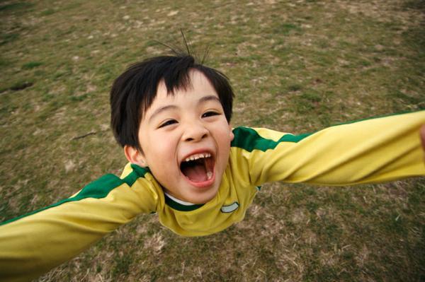 image of a boy looking toward the sky with his arms held wide