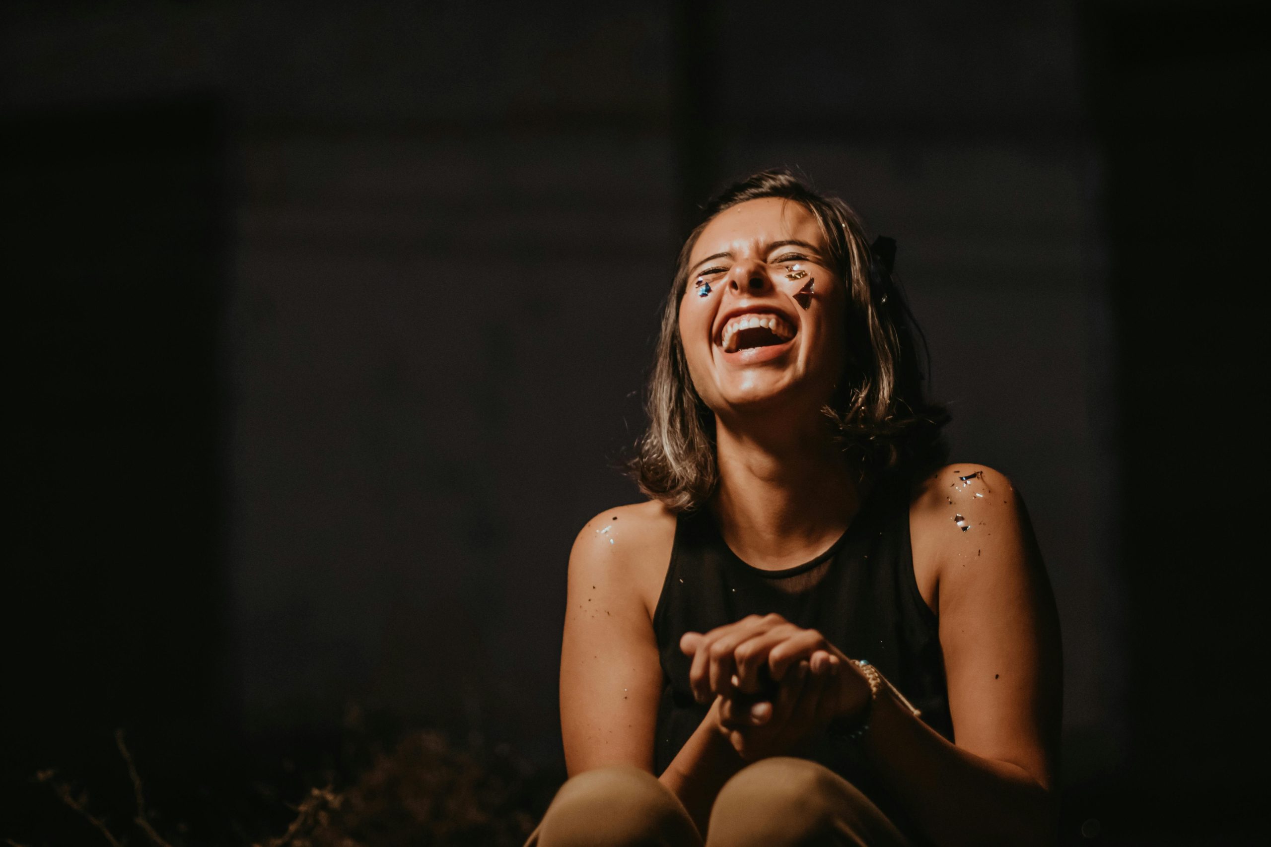 Woman laughing with paint and glitter on her face